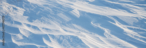 Snow texture. Wind sculpted patterns on snow surface. Wind in the tundra and in the mountains on the surface of the snow sculpts patterns and ridges. Arctic, Polar region. Winter panoramic background. © Andrei Stepanov