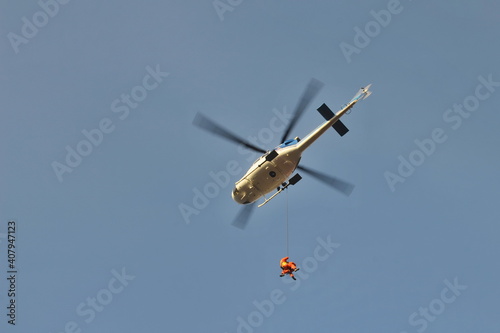 Firefighter rescuer hanging on a rope under a helicopter 