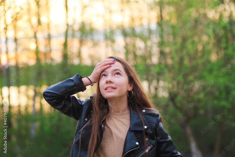 Beautiful Teen Girl is smiling and enjoying nature in the park at Spring sunset Beautiful Teen Girl is smiling and enjoying nature in the park at Spring sunset