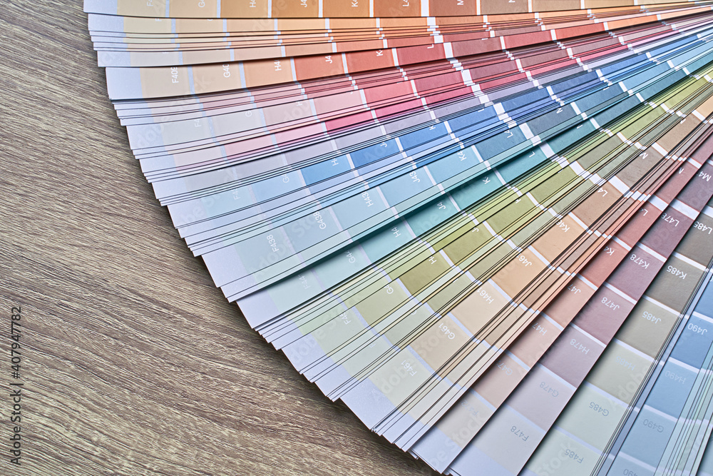 Color wheel palette for choosing paint tone. Various colors on wooden table background with copy space. Interior designer tool.