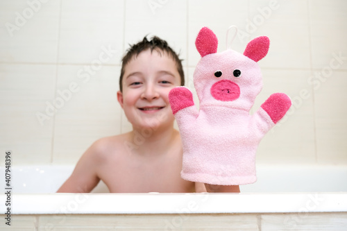 A boy in a bathroom showing funny piggy hand puppet toy washcloth close up, happy washing and shower concept photo