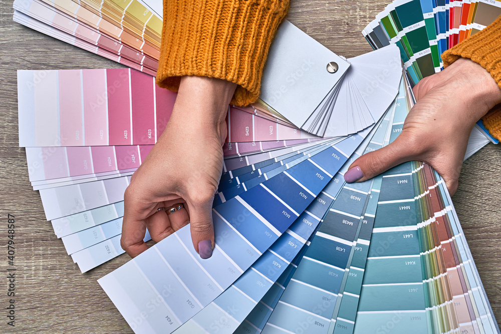 Color wheel for choosing paint tone. Hands of female interior designer working with palette for choosing colors. Creative process concept. Comparing options with matching hues.