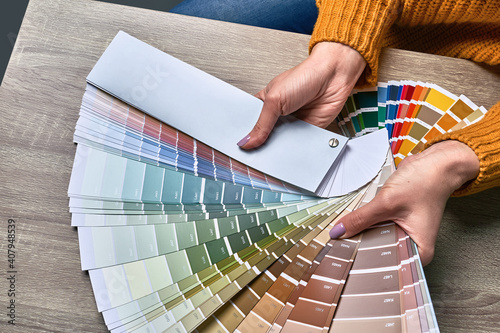 Fototapeta Naklejka Na Ścianę i Meble -  Color wheel for choosing paint tone. Hands of female interior designer working with palette for choosing colors. Creative process concept. Comparing options with matching hues.
