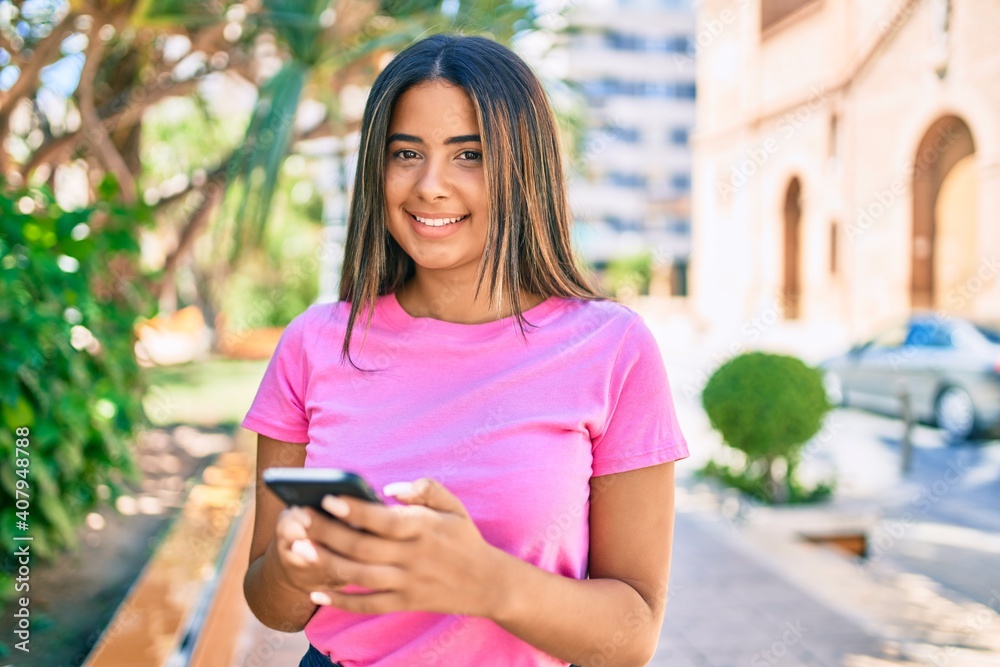 Young latin woman smiling happy using smartphone at the city.