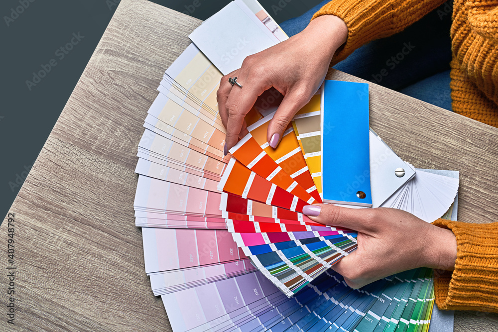 Color wheel for choosing paint tone. Hands of female interior designer working with palette for choosing colors. Creative process concept. Comparing options with matching hues.
