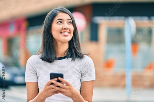 Young hispanic woman smiling happy using smartphone at the city. © Krakenimages.com