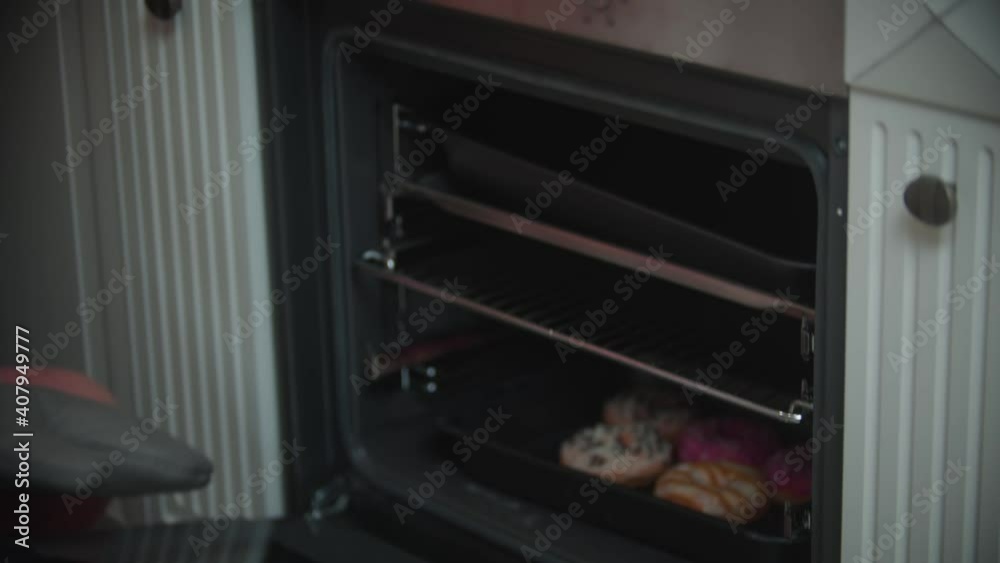 Family christmas - happy woman taking a baking sheet with donuts out the oven Family christmas - happy woman taking a baking sheet with donuts out the oven