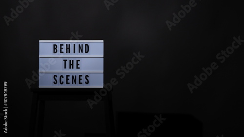 Behind the scenes letterboard text on Lightbox or Cinema Light box. Movie clapperboard and director chair. Background black color. camera shootin in video production studio.