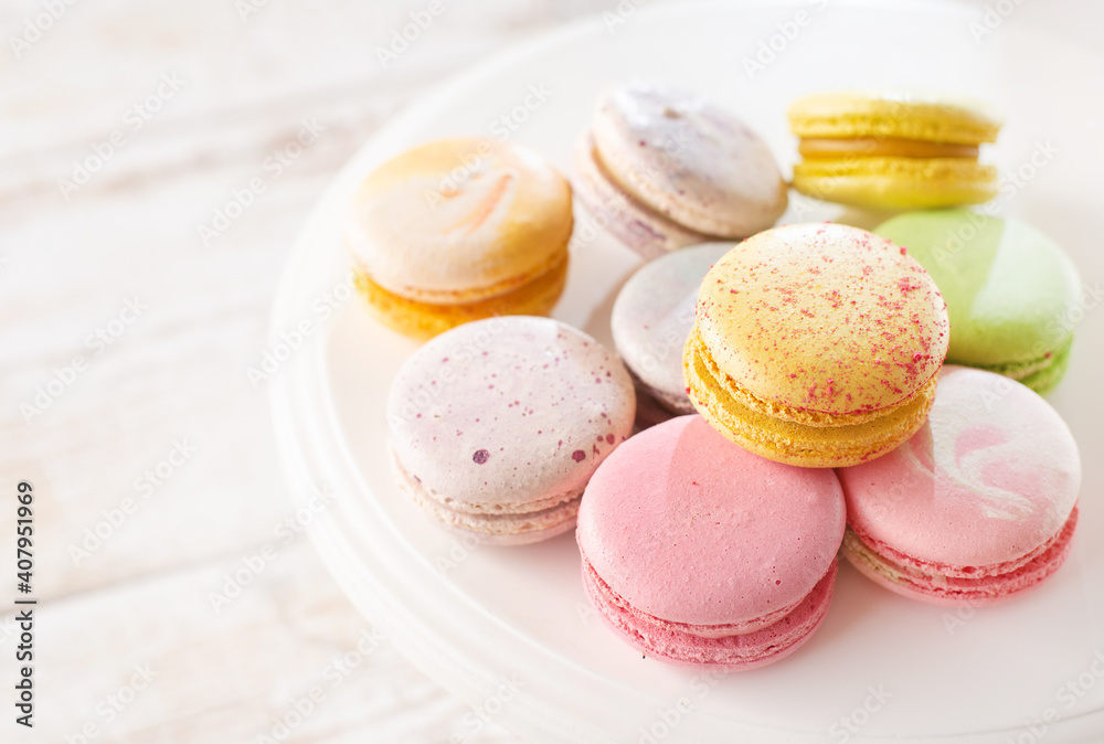 Multi-colored macarons on wood background with soft lights and shadows. Gentle macaroons on table on light background Multi-colored macarons on wood background with soft lights and shadows. Gentle macaroons on table on light background