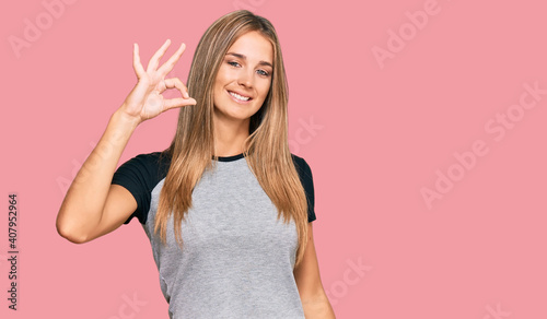 Young blonde woman wearing casual clothes smiling positive doing ok sign with hand and fingers. successful expression.