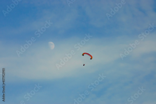 paraglider against the blue sky, the moon in the background