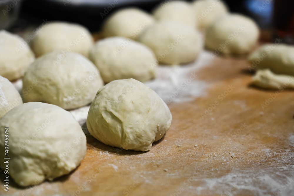 Raw dough balls and flour on wooden counter. Preparation for cooking pastries.