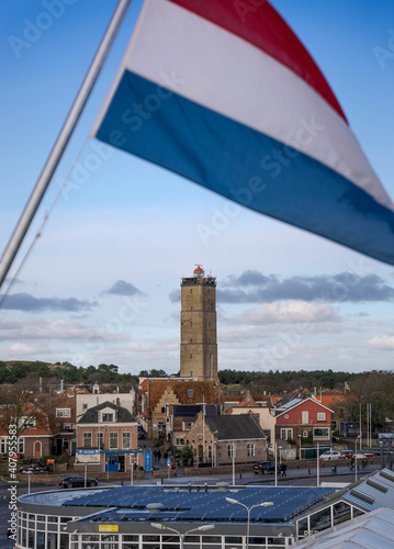 Vertical shot of The Netherlands flag with the Brandaris Lighthouse in the background photo
