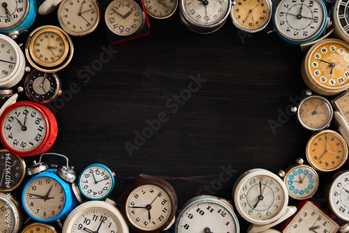 many old  clocks on a dark wooden surface . 