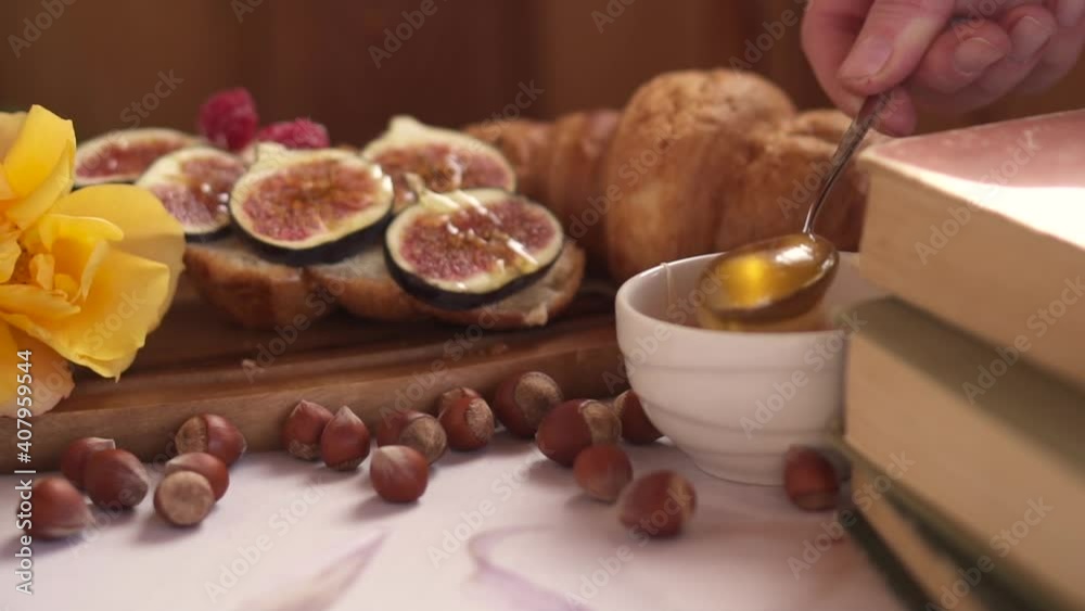 Honey is poured onto the croissant. Gourmet breakfast with fresh pastries and figs. Coffee and nut decor. Cozy snack. High quality FullHD footage Honey is poured onto the croissant. Gourmet breakfast with fresh pastries and figs. Coffee and nut decor. Cozy snack. High quality FullHD footage