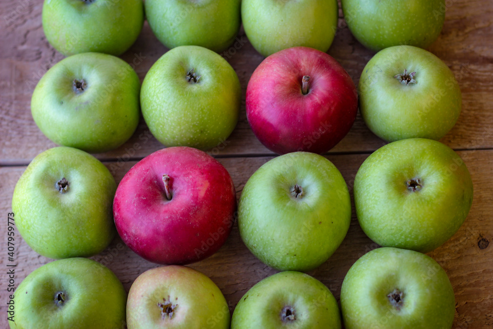 Green and red apples stand on a wooden surface Green and red apples stand on a wooden surface