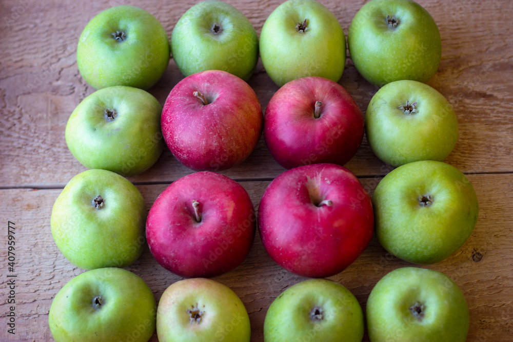 Green and red apples stand on a wooden surface Green and red apples stand on a wooden surface