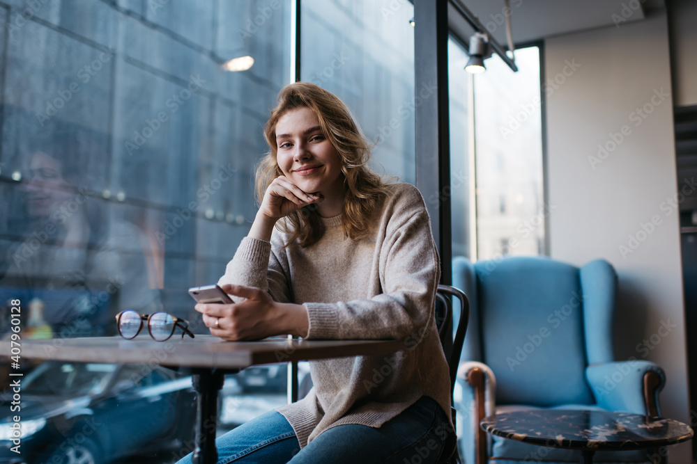 Smiling woman using smartphone at cafe table