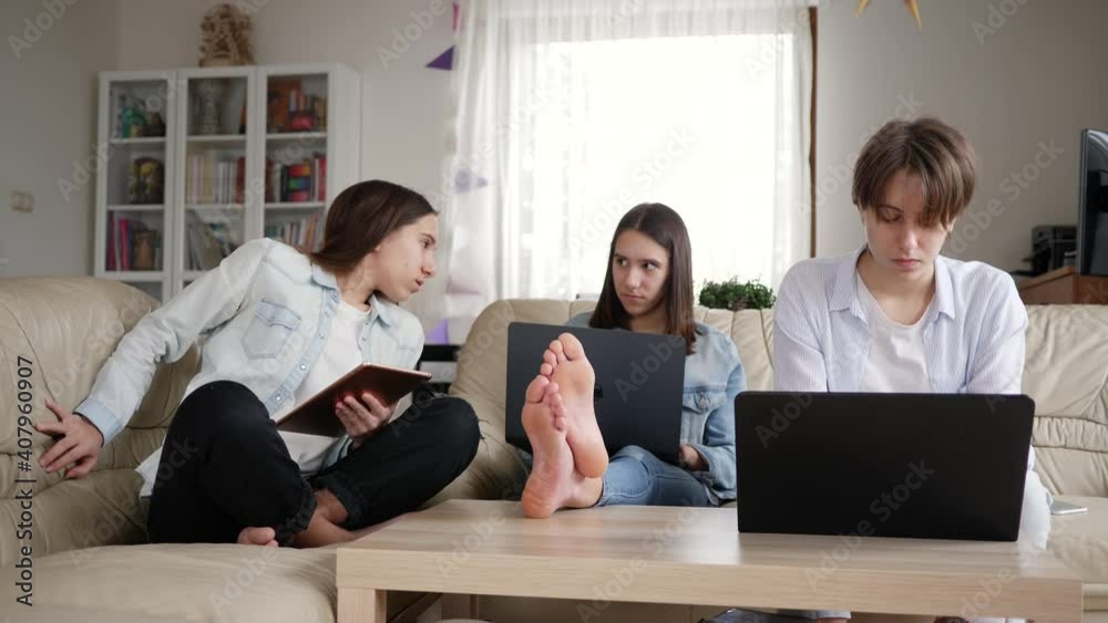 Distance school education at home three triplet sisters teenager girls use laptop computers and tablet for learning preparing lessons making tasks together Distance school education at home three triplet sisters teenager girls use laptop computers and tablet for learning preparing lessons making tasks together