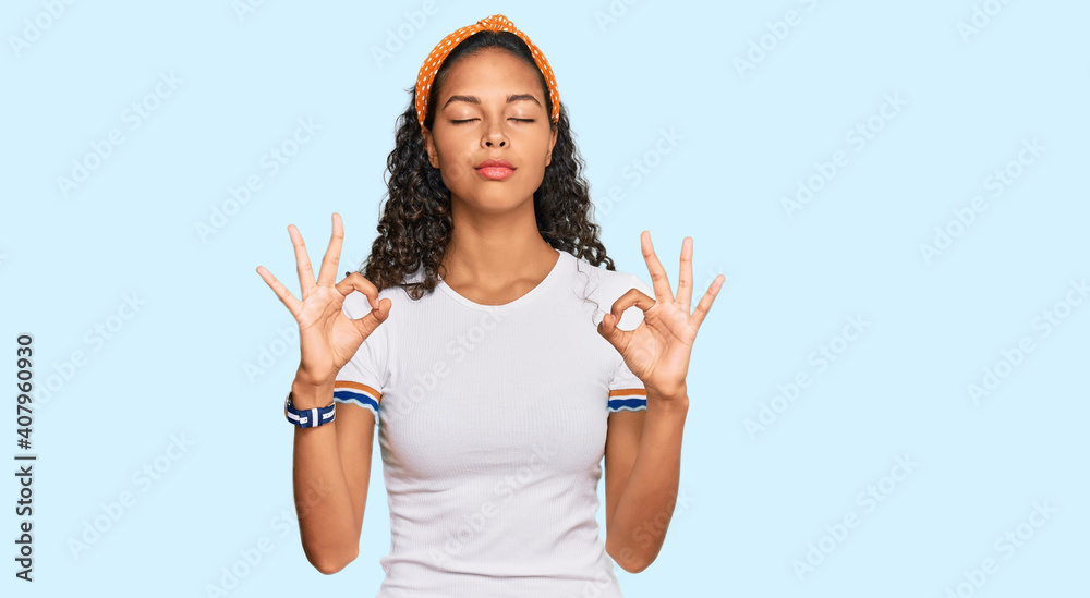 Young african american girl wearing casual clothes relaxed and smiling with eyes closed doing meditation gesture with fingers. yoga concept. Young african american girl wearing casual clothes relaxed and smiling with eyes closed doing meditation gesture with fingers. yoga concept.