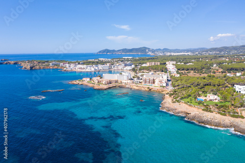 Aerial drone photo of the beautiful island of Ibiza in Spain showing the costal front golden sandy beaches with people relaxing and sunbathing on a hot sunny summers day © Duncan