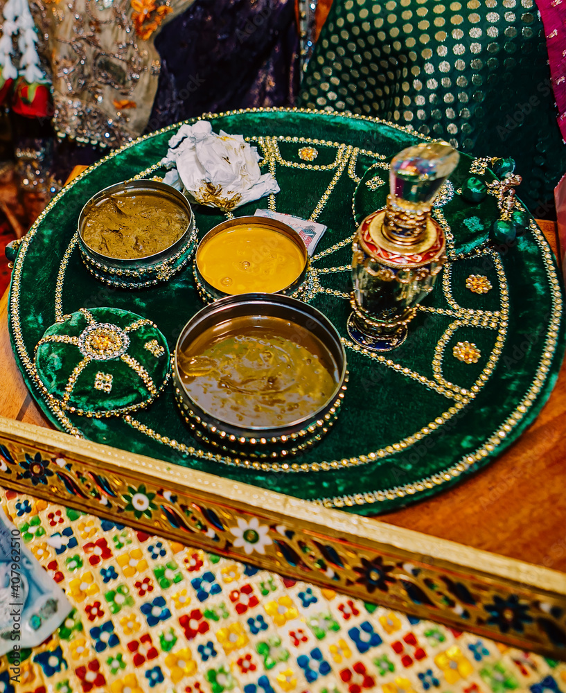 Fototapeta premium Mehndi round emerald green plate on table with open boxes of golden haldi for wedding henna party 