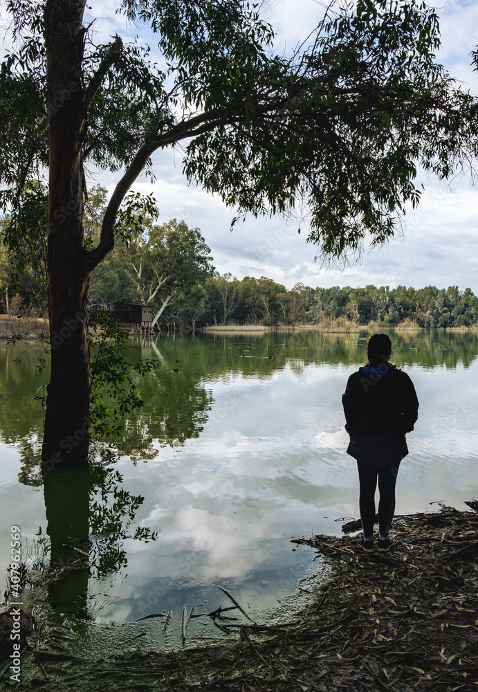 Unrecognised person standing and enjoying the scenery at a lake.