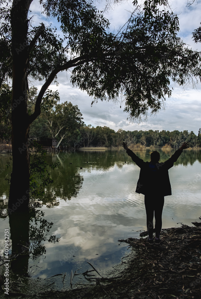 Unrecognised person standing and enjoying the scenery at a lake.
