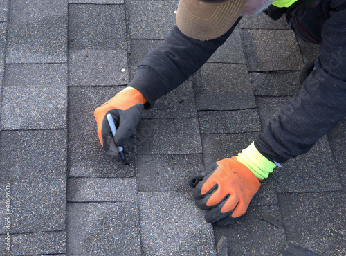 Professional roofer uses a marking pen to color the nail heads black so they will blend with the shingles.