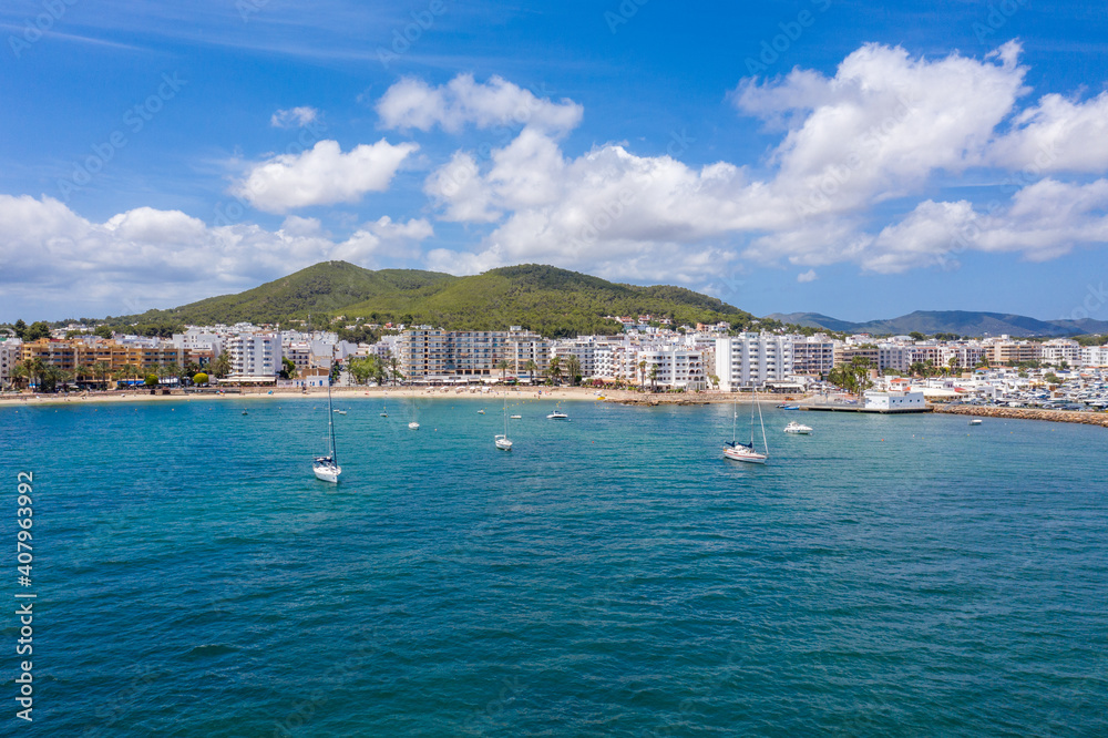 Obraz premium Aerial drone photo of the beautiful island of Ibiza in Spain showing the costal front golden sandy beaches with people relaxing and sunbathing on a hot sunny summers day