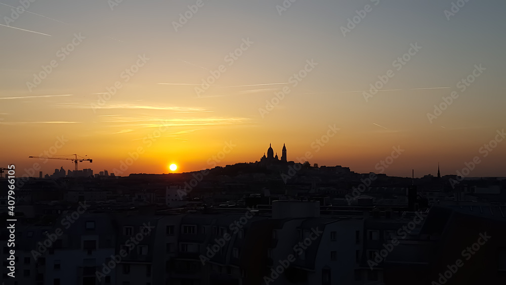 Relaxing sunset on a clear day in Paris. The colors of the sky shine in purple, red and orange. The silhouette of the church Sacre Coeur in Montmartre is in the background. 