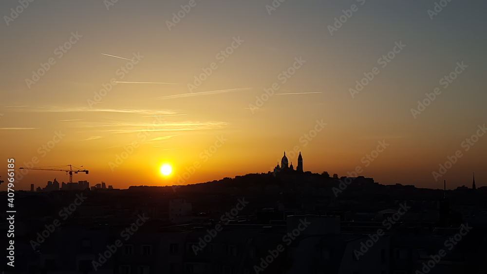 Relaxing sunset on a clear day in Paris. The colors of the sky shine in purple, red and orange. The silhouette of the church Sacre Coeur in Montmartre is in the background. 