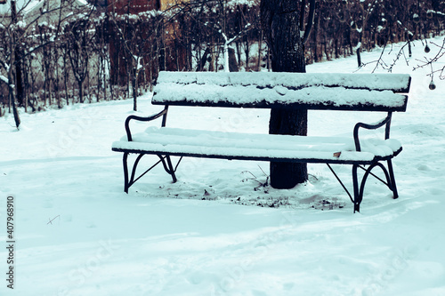 Old bench in the snow covered garden.