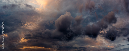 wide panoramic view of the dramatic sunset sky with dark cumulus clouds and natural purple-orange illumination from the evening dawn. Artistic backdrop for atmospheric design or decoration