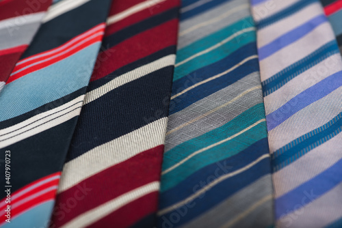 close-up view, many colorful folded ties, sloping horizon. Textured background of classic fabrics