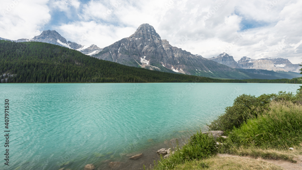 Canadian Rockies with glaciers in the mountains and a large turquoise lake.