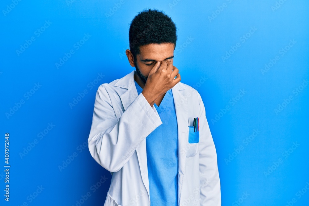 Handsome hispanic man with beard wearing doctor uniform tired rubbing nose and eyes feeling fatigue and headache. stress and frustration concept. Handsome hispanic man with beard wearing doctor uniform tired rubbing nose and eyes feeling fatigue and headache. stress and frustration concept.