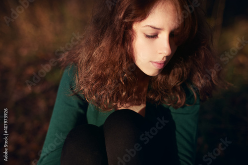 Young caucasian woman with brown hair resting in autumnal park. Close-up head and shoulders.