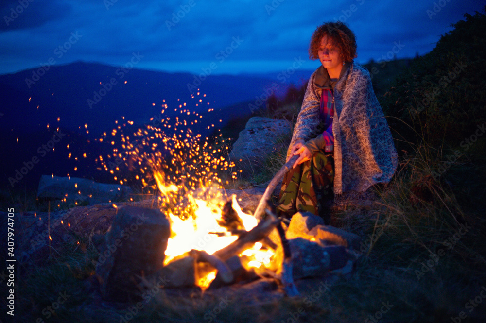 Young caucasian woman near the bonfire at night in the mountains. Young caucasian woman near the bonfire at night in the mountains.