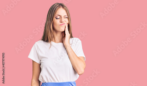 Young beautiful blonde woman wearing summer style touching mouth with hand with painful expression because of toothache or dental illness on teeth. dentist