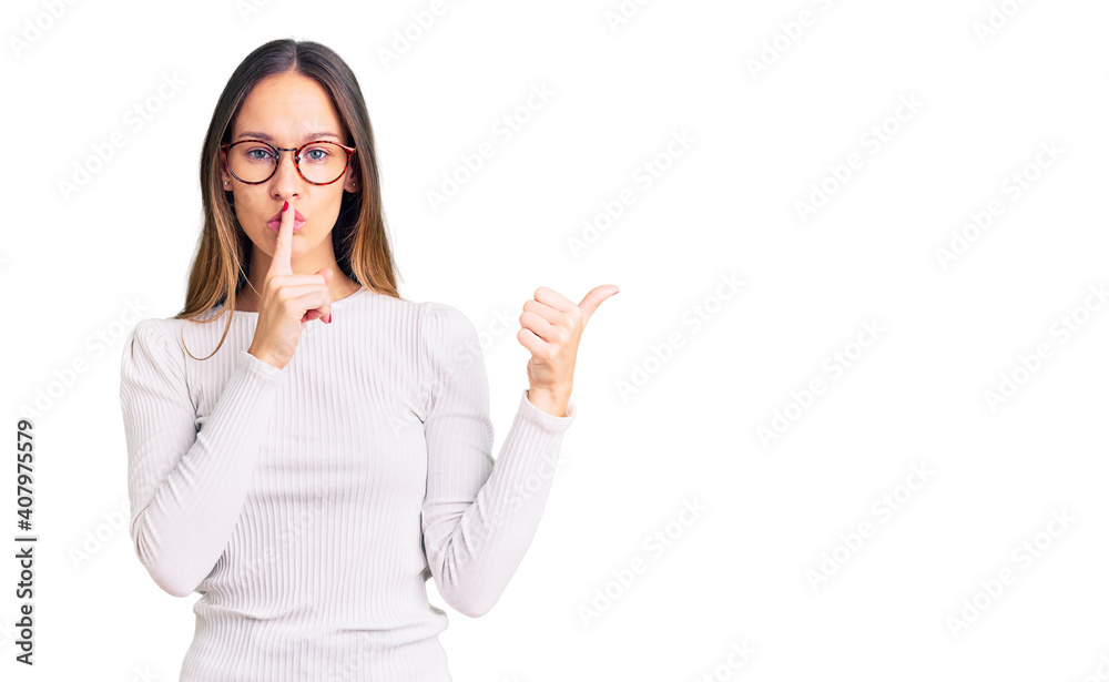 Beautiful brunette young woman wearing casual white sweater and glasses asking to be quiet with finger on lips pointing with hand to the side. silence and secret concept. Beautiful brunette young woman wearing casual white sweater and glasses asking to be quiet with finger on lips pointing with hand to the side. silence and secret concept.