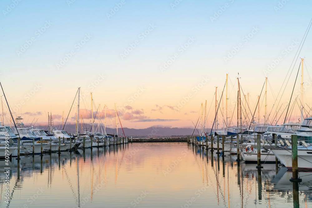 Tauranga Marina boats and piers reflected in calm water at sunrise Tauranga Marina boats and piers reflected in calm water at sunrise
