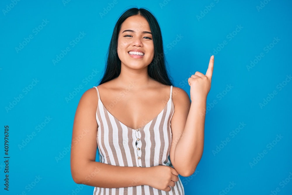 Young beautiful asian girl wearing casual clothes with a big smile on face, pointing with hand and finger to the side looking at the camera. Young beautiful asian girl wearing casual clothes with a big smile on face, pointing with hand and finger to the side looking at the camera.