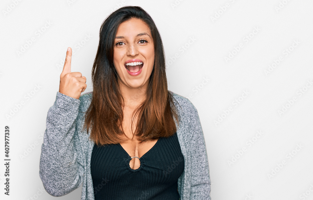 Beautiful hispanic woman wearing casual clothes pointing finger up with successful idea. exited and happy. number one. Beautiful hispanic woman wearing casual clothes pointing finger up with successful idea. exited and happy. number one.