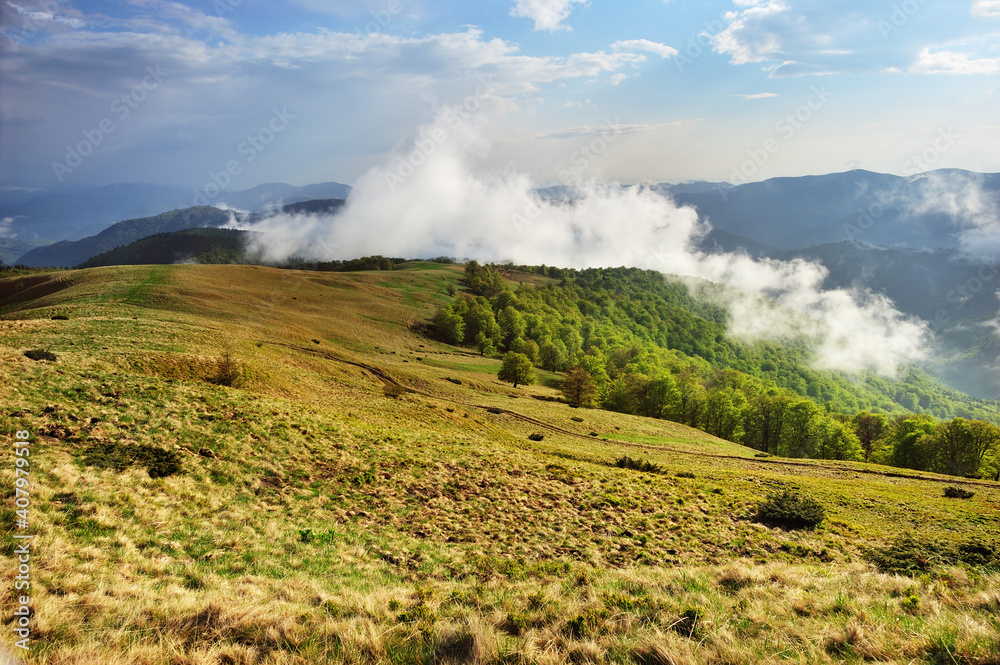 Panoramic view of a mountain range in the fog in cloudy summer weather at sunset. Panoramic view of a mountain range in the fog in cloudy summer weather at sunset.