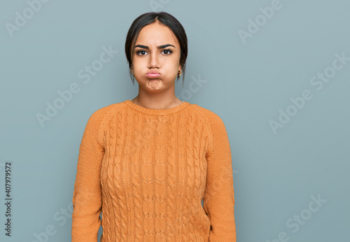 Young brunette woman wearing casual winter sweater puffing cheeks with funny face. mouth inflated with air, crazy expression.