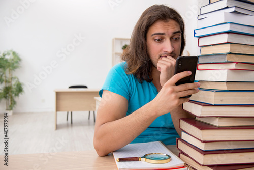 Young male student and a lot of books in the class