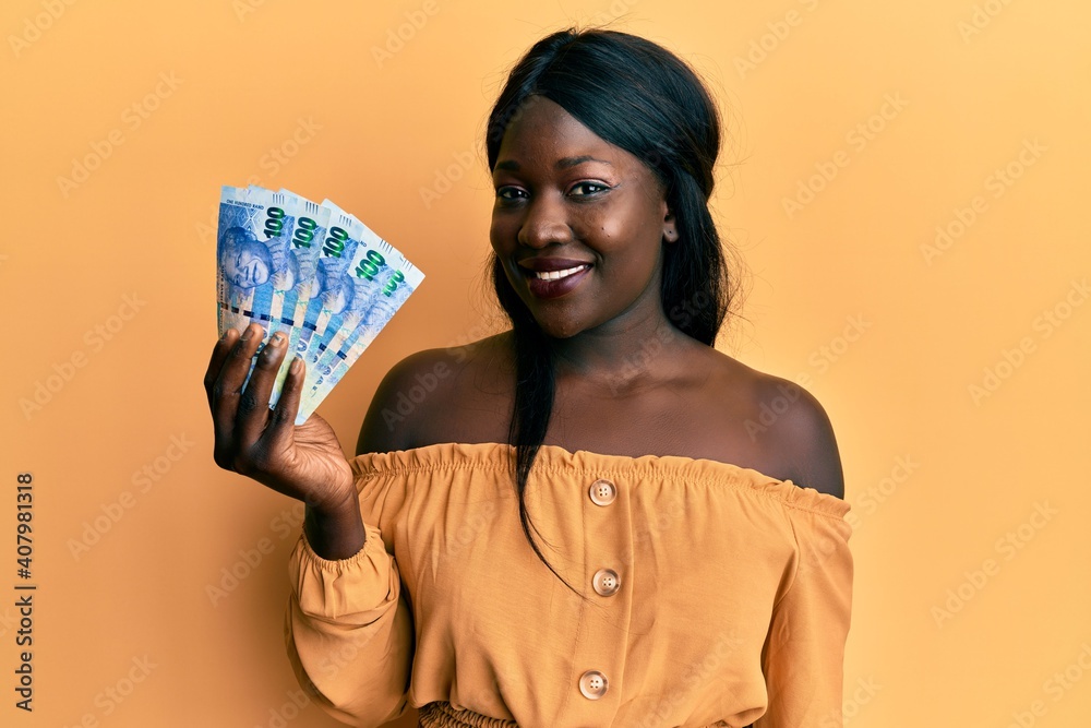 African young woman holding south african 100 rand banknotes looking positive and happy standing and smiling with a confident smile showing teeth African young woman holding south african 100 rand banknotes looking positive and happy standing and smiling with a confident smile showing teeth