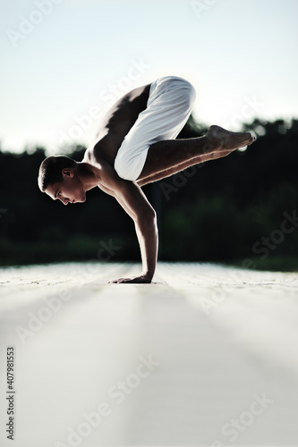 Young caucasian brunette man doing yoga in the park at sunset.
