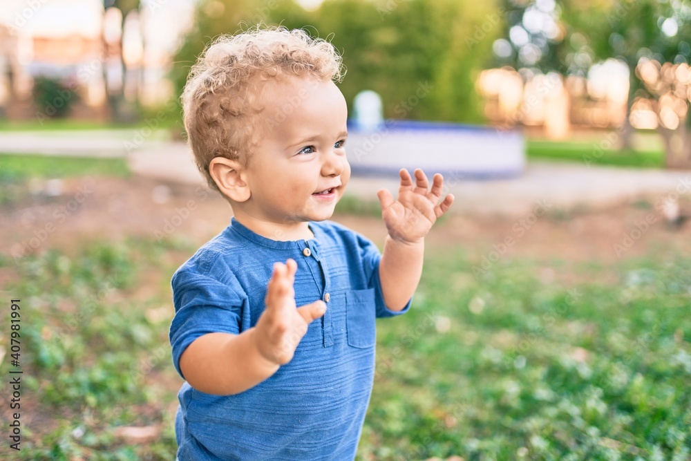 Cute and happy little boy having fun at the park on a sunny day. Beautiful blonde hair male toddler playing outdoors Cute and happy little boy having fun at the park on a sunny day. Beautiful blonde hair male toddler playing outdoors